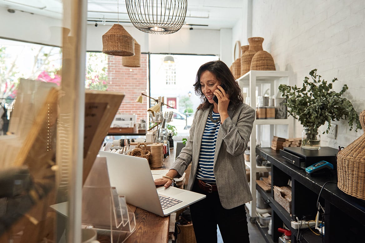 Small shop owner on a call looking at her laptop