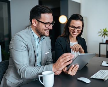 Coworkers looking at a tablet at their desk