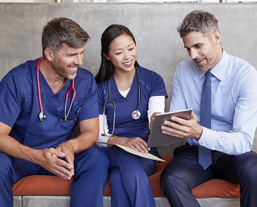 Three healthcare workers sit using tablet together
