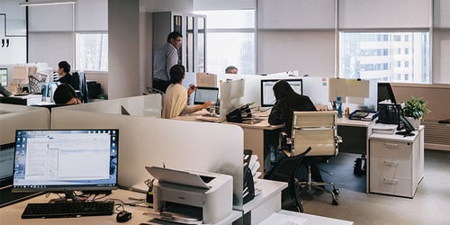 A group of people in an office work independently at their individual desks.