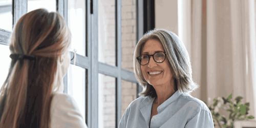 An older woman smiling at a younger woman.