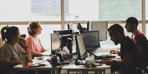 People sit in a pod working on their individual computers.