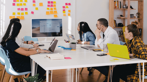 A group of people sit at a conference room table having a discussion.