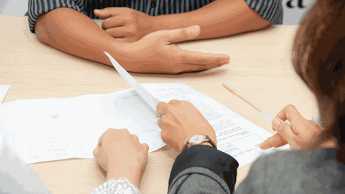 People sit across from one another reviewing paperwork.