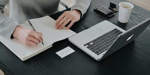 A person working and writing at their computer.