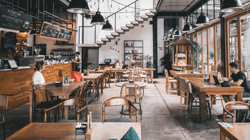 People eat and work on their laptops in a sparsely populated cafe