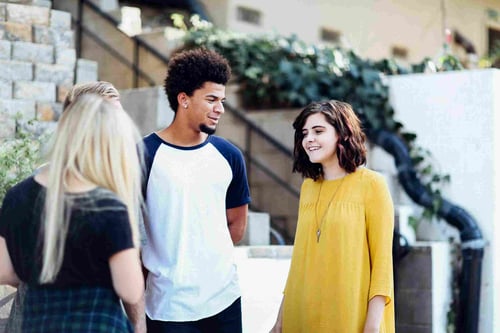 A group of teens stands outside of a community building