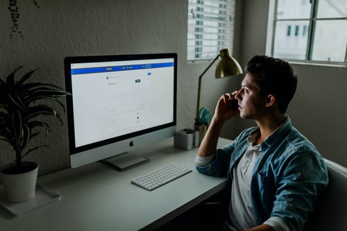 A person works in a dark office at their computer while on the phone