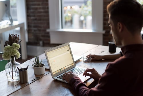 A person works on their laptop from a dark office space