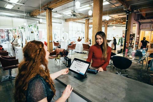 A person cashes out with the person behind the counter at a cafe