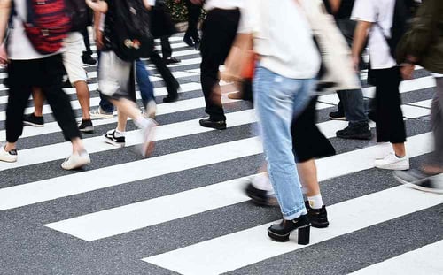 A crowd of people walk in a cross walk