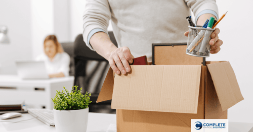 A person packs their office belongings into a cardboard box 