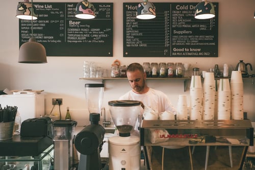 A coffee shop worker brews a fresh pot behind the counter