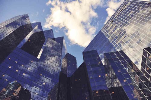 Large mirrored buildings with blue sky and white clouds above