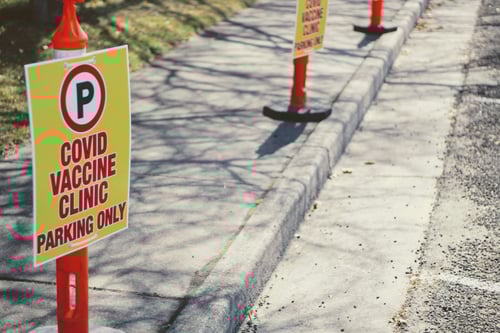 A parking sign for covid-19 vaccinations is on the street curb