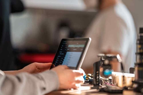 A person sits at their desk reviewing information on a tablet device