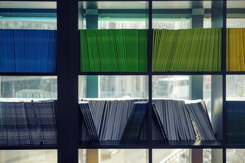 A shelf neatly filled with different colored files