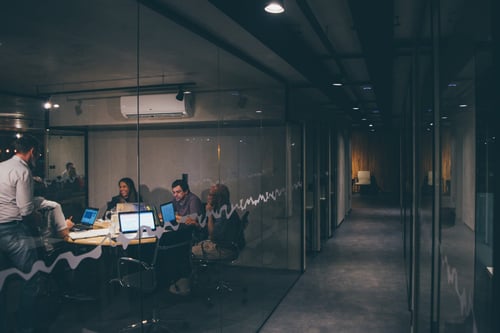 A group of people work in a dimly lit conference room