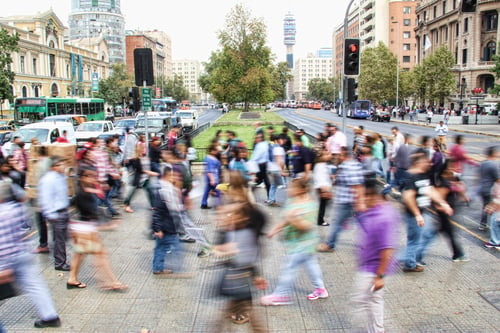 A crowd of people walk through a busy city street