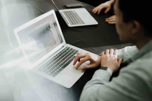 A person scrolls on their laptop