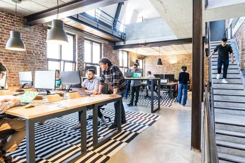 Groups of people work at standing desks and having discussions with one another