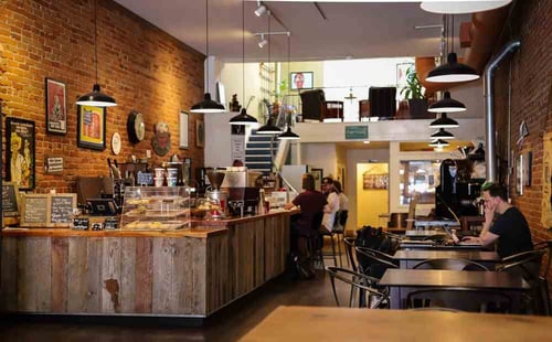 People are working at tables in small coffee shop