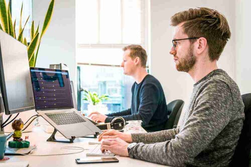 Two people work independently at a shared desk