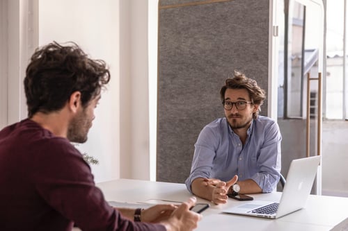 Two people sit in a modern style conference room having a discussion