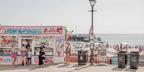 A beach side ice cream stand with patrons getting their order.