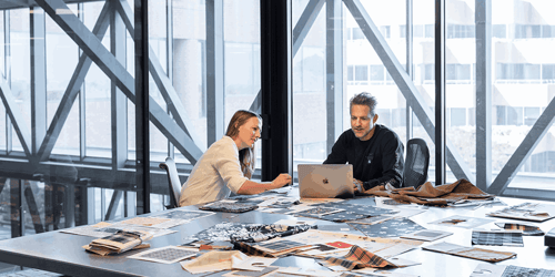 Two people sit in a conference room collaborating. 