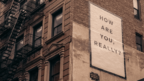 A brick apartment building has a mural with the words 