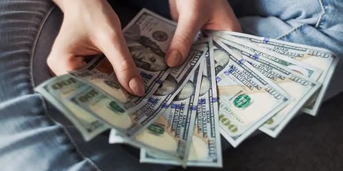 A person counting money with only their hands in view.