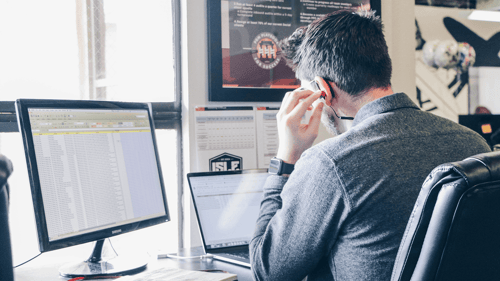 Someone looks at multiple screens while listening to their earbud.