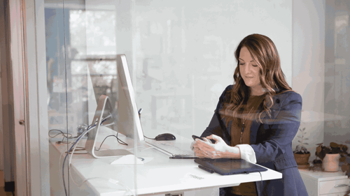 Person standing at their desk reviewing a message on their phone.