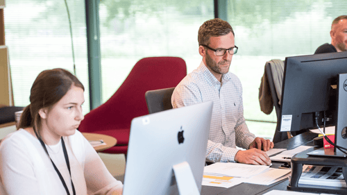 Three people work alongside one another at their own computers.