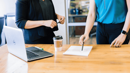 Two people stand at a table reviewing paperwork