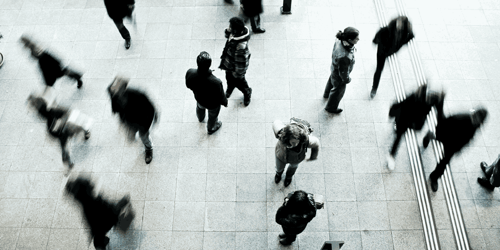 Individuals and groups of people walk through a crowded area.