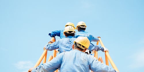 Workers climbing the stairs while wearing hard hats.