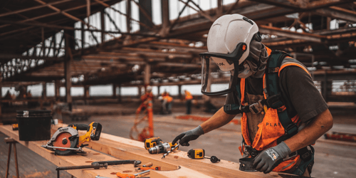 A construction worker leans over a piece of plywood while working on a job site. 