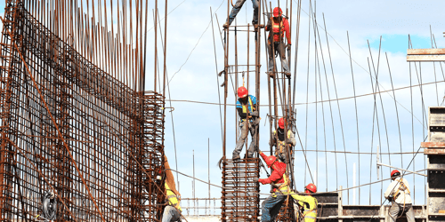 Several construction workers in hard hats work together on a project. 