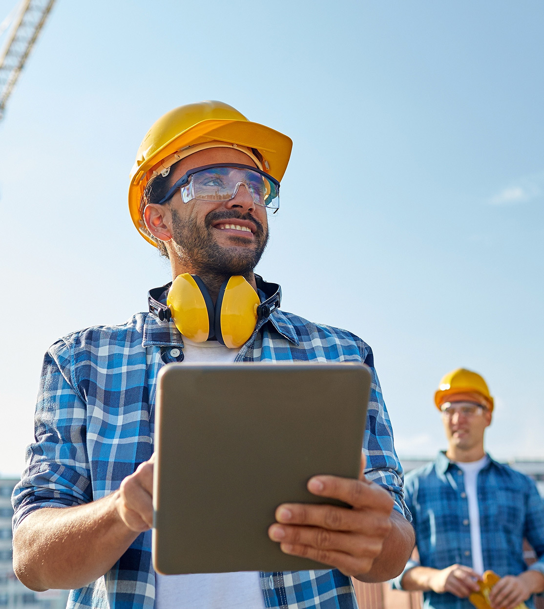 Builder in hardhat with tablet at construction site