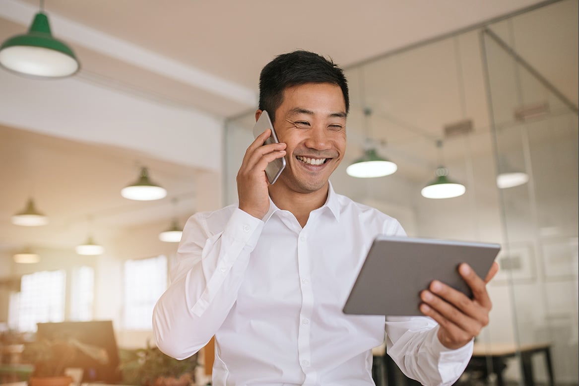 Cheerful professional on a call while looking at his tablet