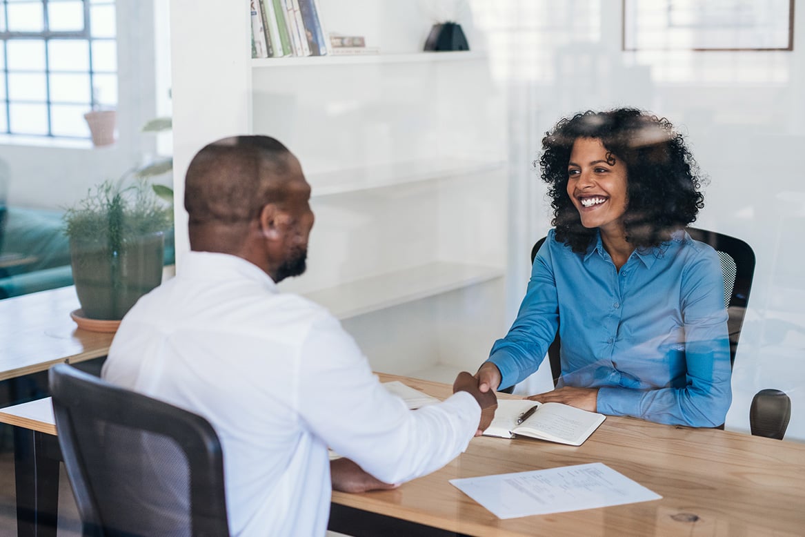 Manager and employee shaking hands in an office