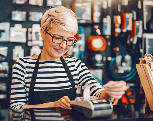 Smiling worker using cash register in bicycle store