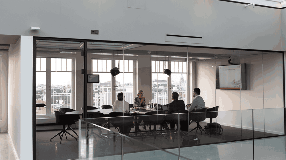 A group of people sit in a conference room around a table.