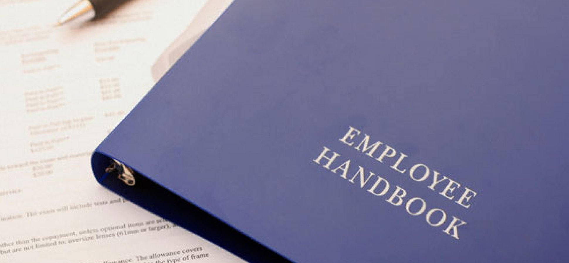 An employee handbook sits on top of a stack of papers