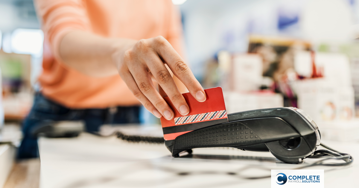 A person swipes their credit card at a store card reading terminal