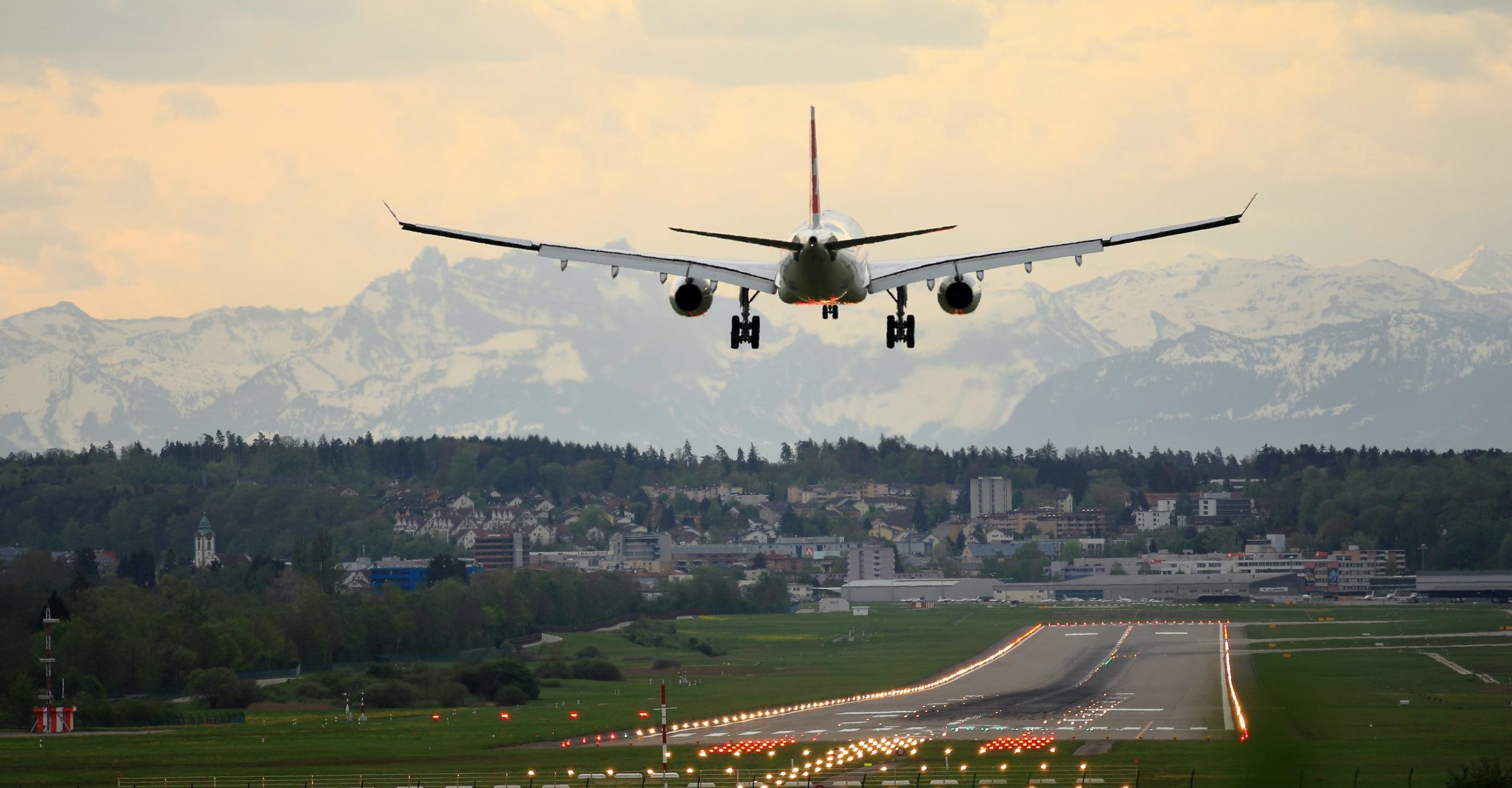 An airplane lands. A mountain view is in the distance.