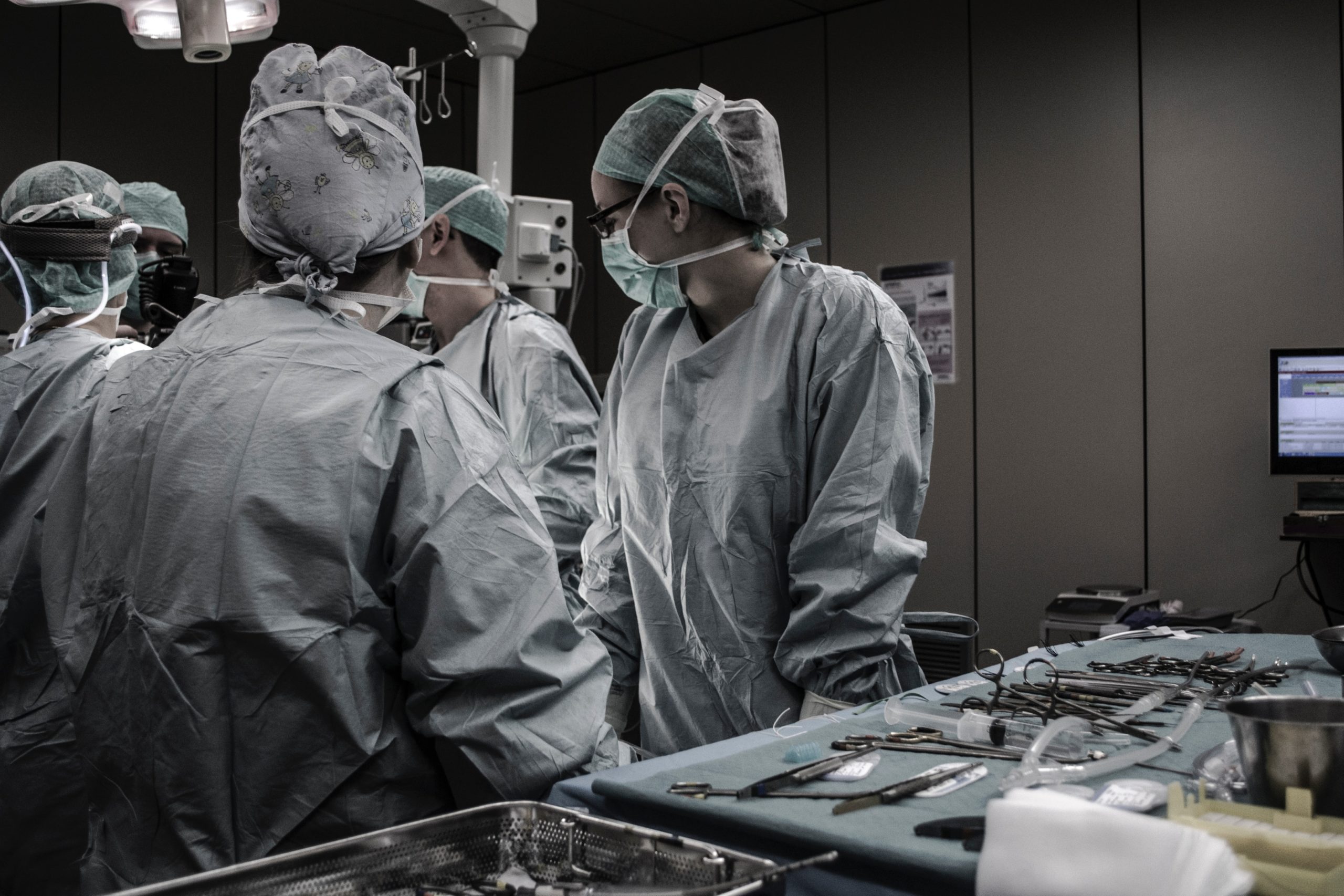 A group of medical professionals stand in an operating room performing a procedure.
