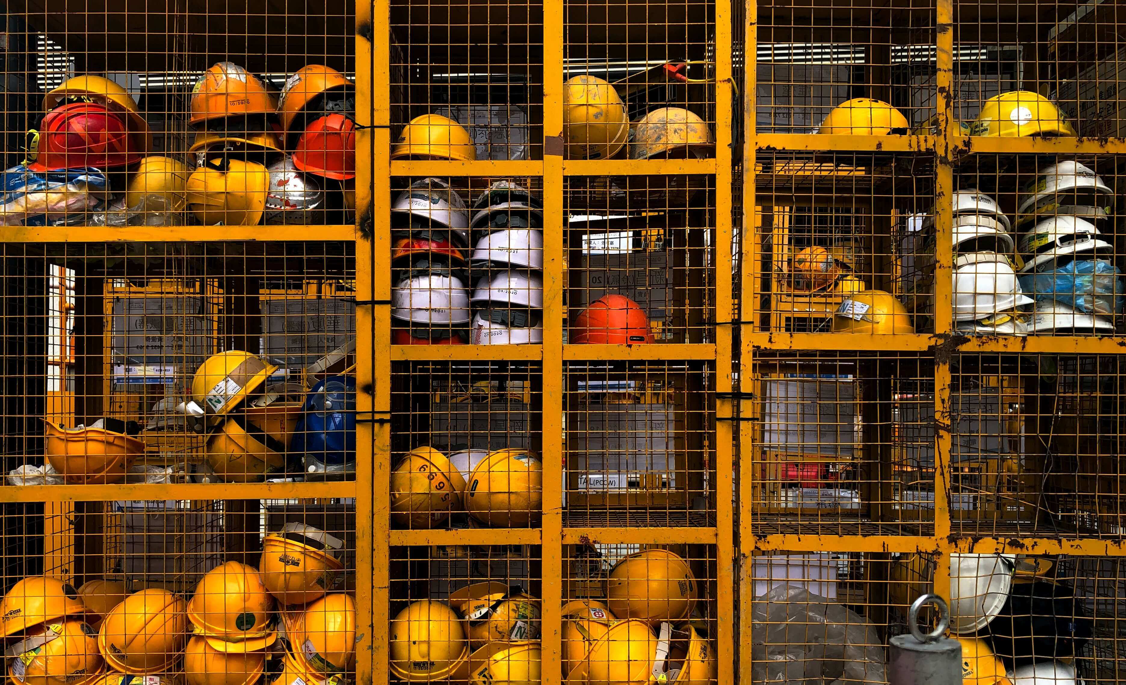A caged storage unit is filled with hard hats